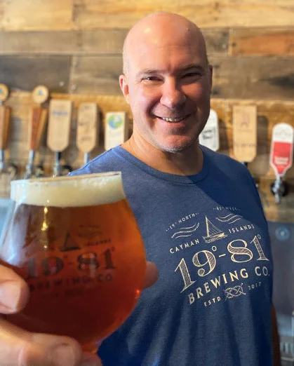 Brewer holds glass of 19-81 Brewing Co. beer at brewery taproom.