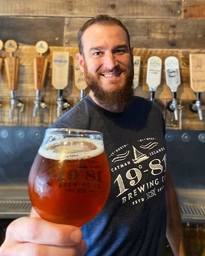 Brewer holds glass of 19-81 Brewing Co. beer at taproom.