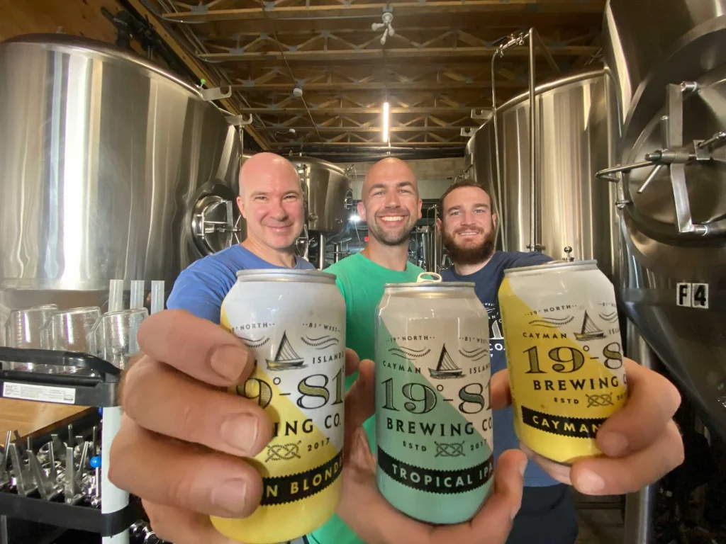 19-81 Brewing Co. brewers hold craft beer cans inside the brewery.
