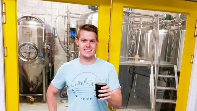 Man enjoys fresh craft beer at Cayman Brewery tour.