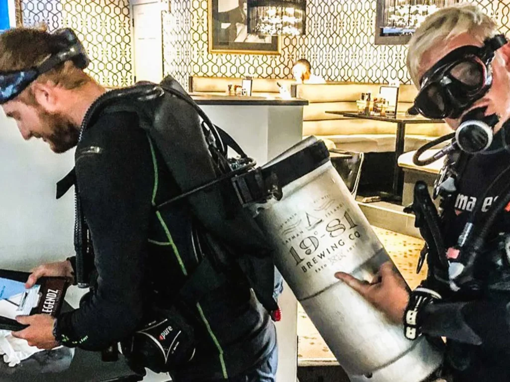 Scuba divers deliver 19-81 Brewing Co. keg indoors.