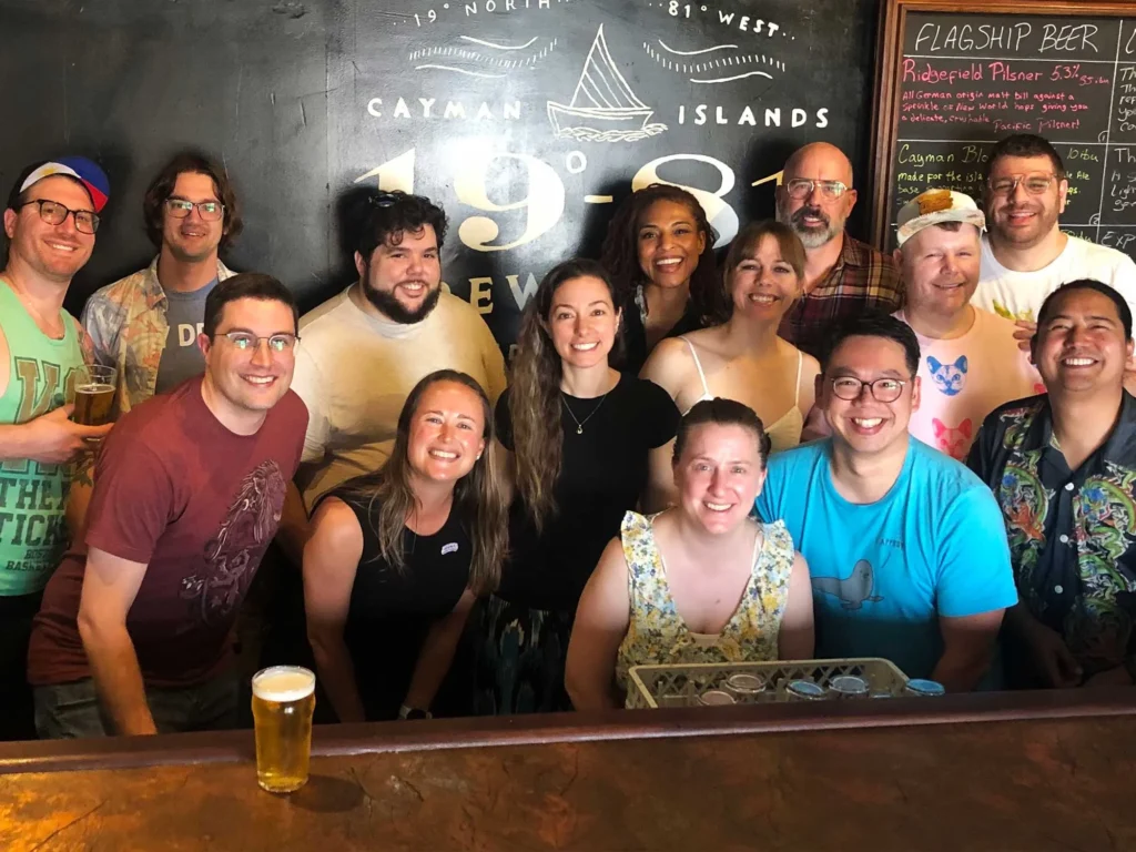 Friends smile at Cayman Islands Brewery, 1981 logo behind.