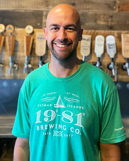 John Mather smiles in a 1981 Brewing Co. shirt by beer taps.