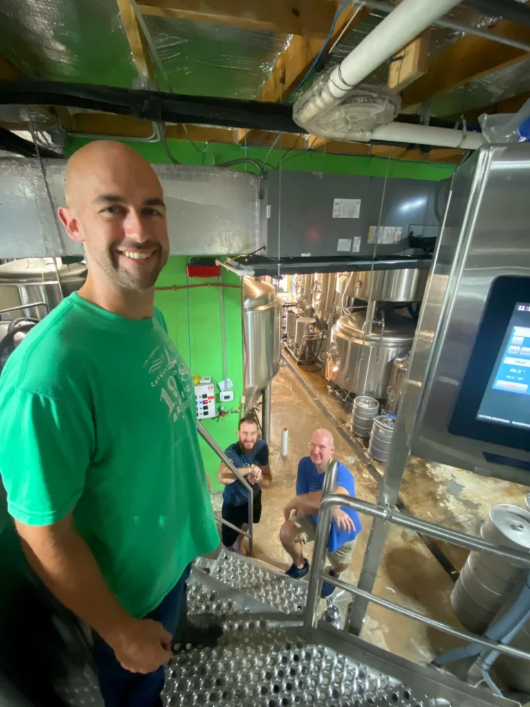Brewery team inspects stainless steel equipment in brewhouse.