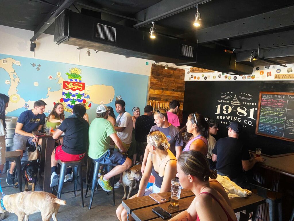 Group of people enjoying craft beers with their dogs at 1981 Brewing Co. taproom in George Town, Cayman Islands.