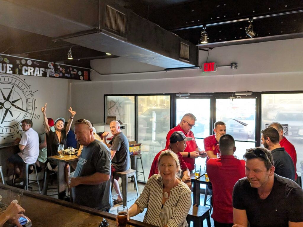 A group of people socializing and drinking beer inside the 19-81 Brewing Co. taproom.