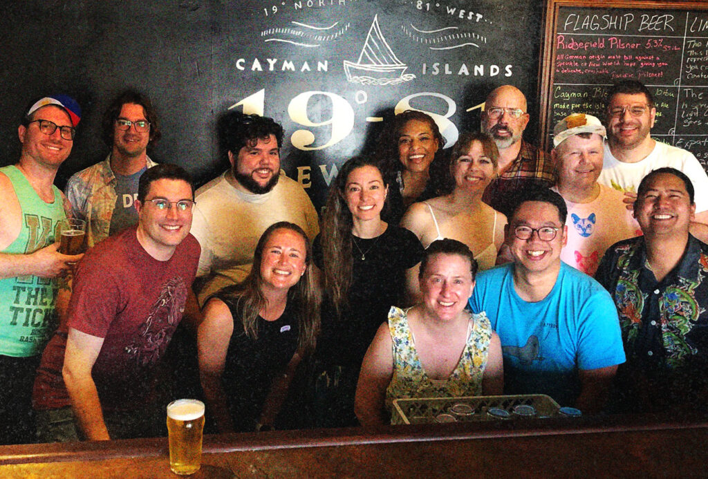 A group of people smiling and enjoying themselves at the 19-81 Brewing Co. taproom bar.