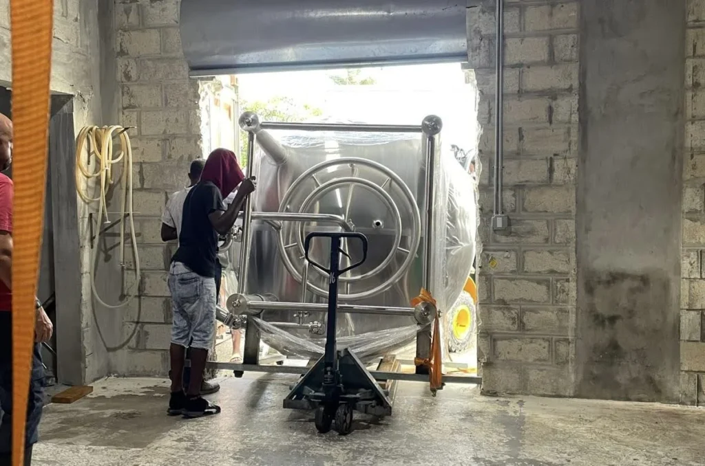 Brewery workers install new, large, stainless steel tank.
